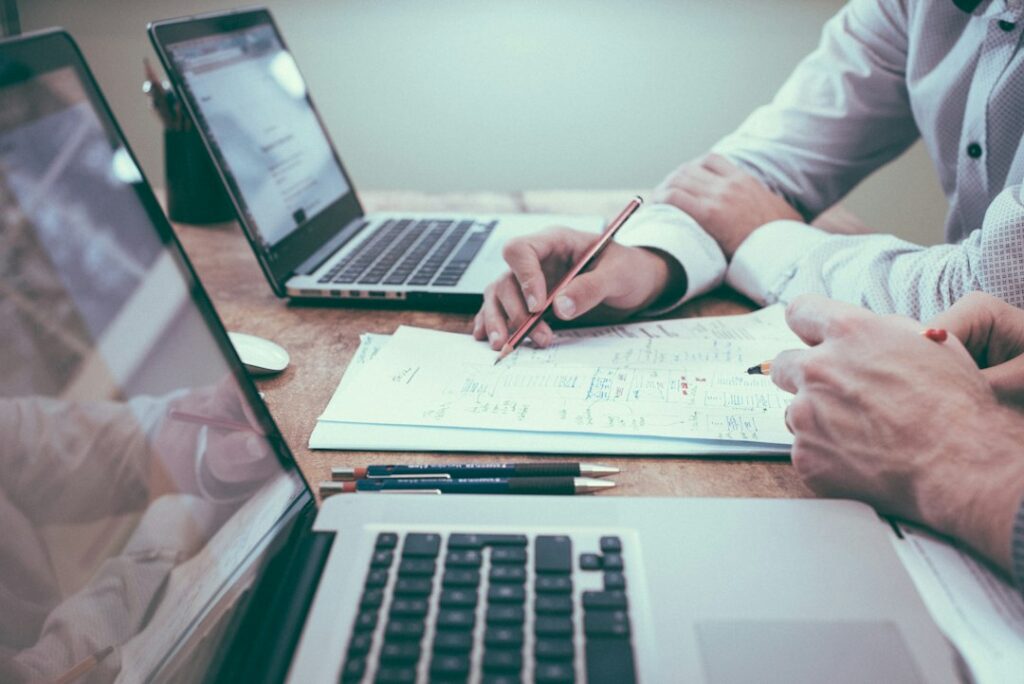 People reviewing printed business records beside a laptop